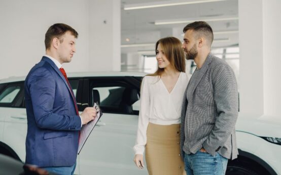 A couple discussing car purchase options with a salesperson in a modern showroom.